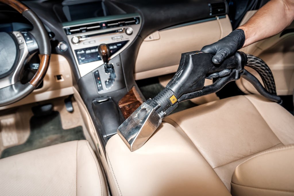 Professional detailing specialist vacuuming car interior. Detailing cleaning car with steam