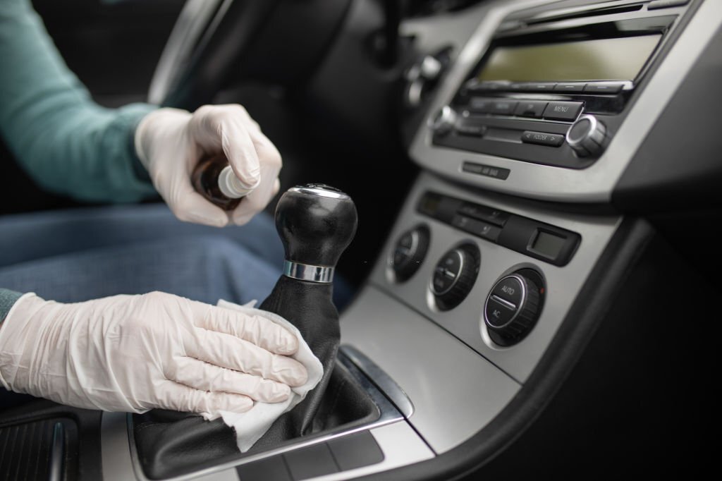 Person disinfecting and cleaning car interior with antiseptic liquid and wet disinfection wipes. Gearshift is one of dirtiest parts in car and can contains viruses and bacteria.