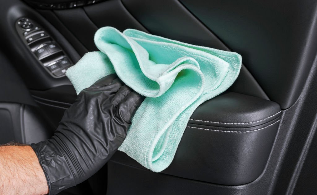 A man cleaning car seat with blue microfiber cloth. Car detailing or valeting concept. Selective focus. Car detailing. Cleaning with sponge. Worker cleaning. Car wash concept solution to clean