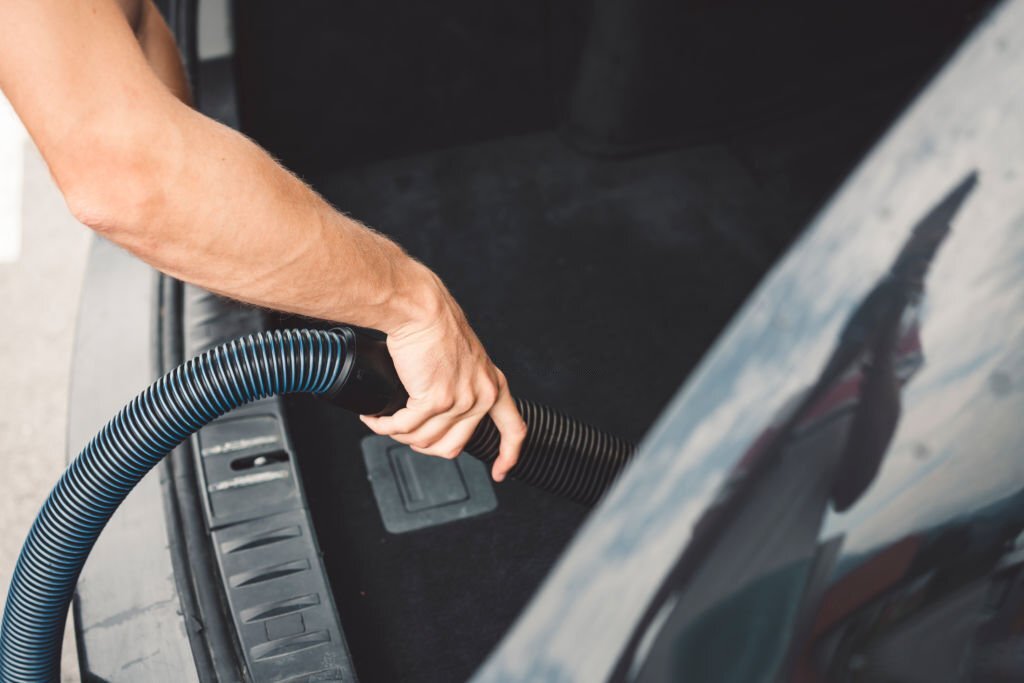 Man is vacuuming the indoors of his car