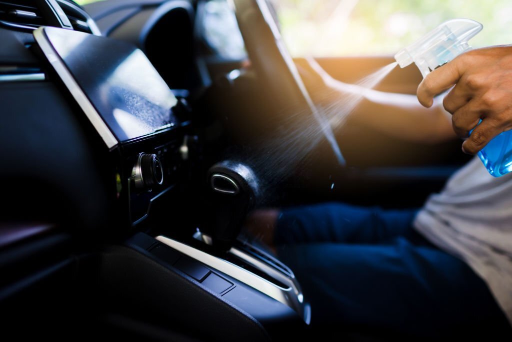 Hand of driver is spraying alcohol to gearshift stick to kill the Coronavirus (Covid 19) or contamination of germ. Driver is cleaning and wipe surfaces that are frequently touch with spraying alcohol.