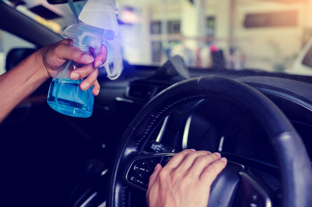 Hand of driver is spraying alcohol to car steering wheel to kill the Coronavirus Covid19 or contamination of germ. Driver is cleaning and wipe surfaces that are frequently touch with spraying alcohol.