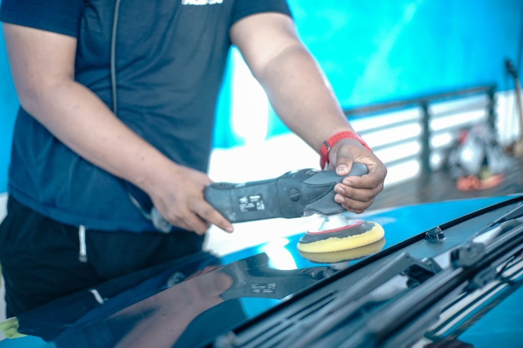 Asian man uses car polishing tools to maintain car's paintwork