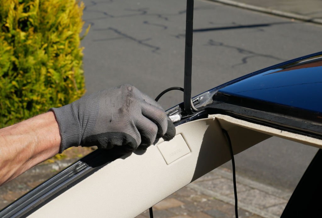 Specialist automotive workers who replace the windshield or windshield of a car in front of a building. Removing silicone.