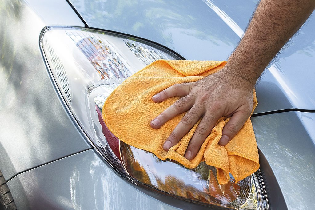 Hand with microfiber cloth cleaning car, Close up