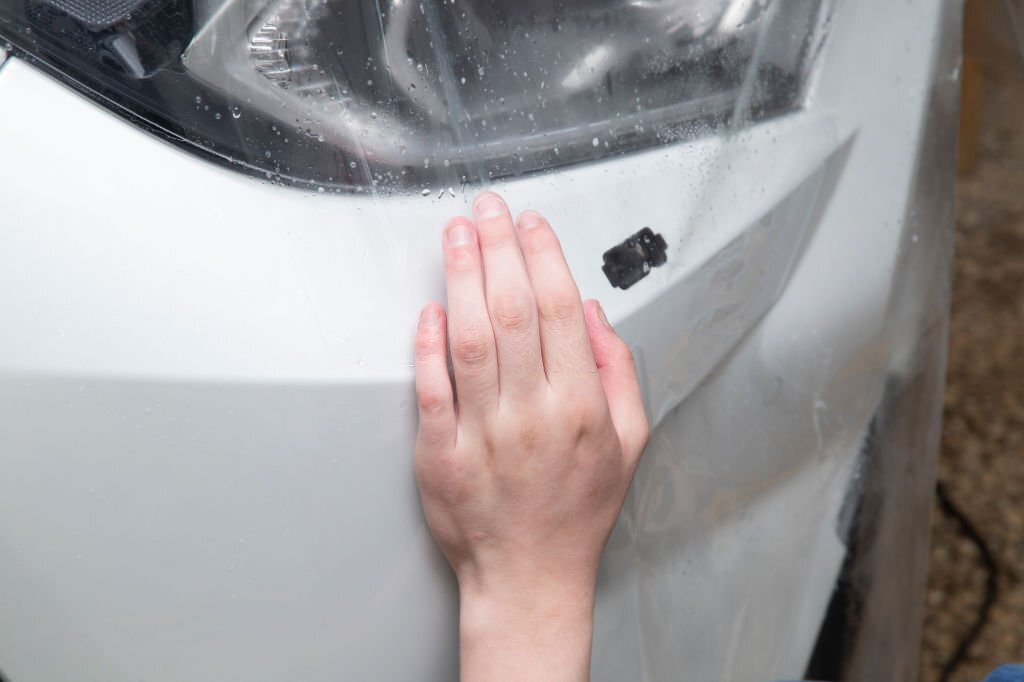 Car wrapping specialist putting transparent vinyl film on car hood.Applying a protective film to the car for protect car paint.