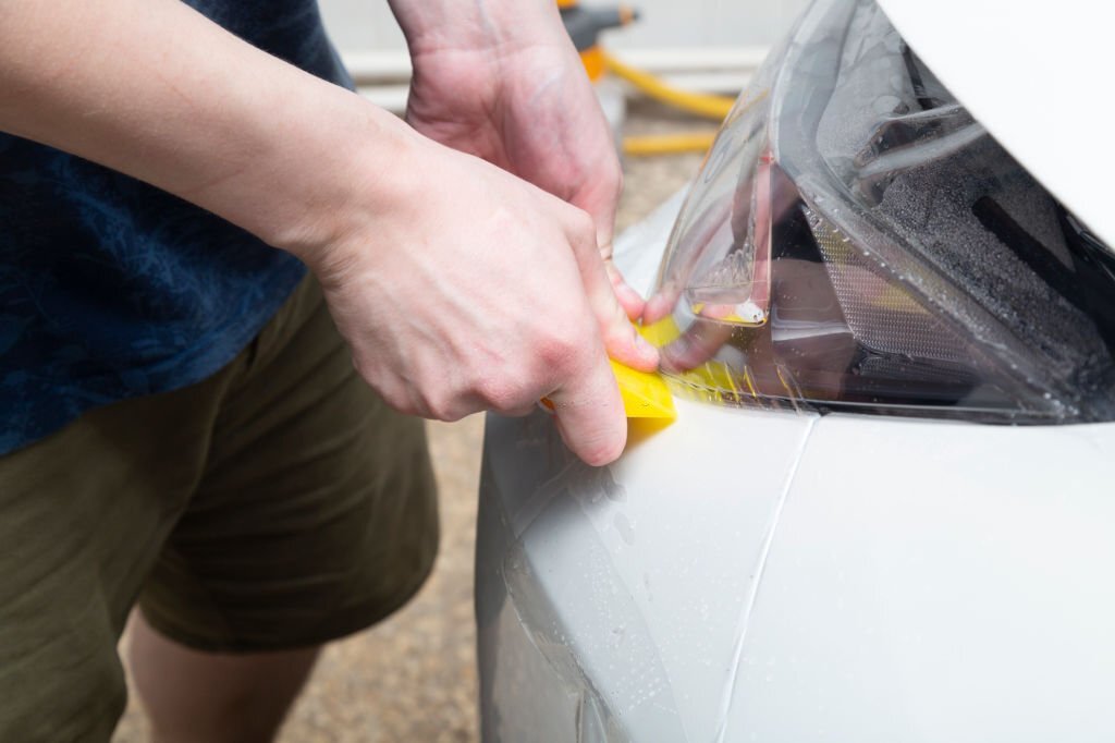 Car wrapping specialist putting transparent vinyl film on car hood.Applying a protective film to the car for protect car paint.